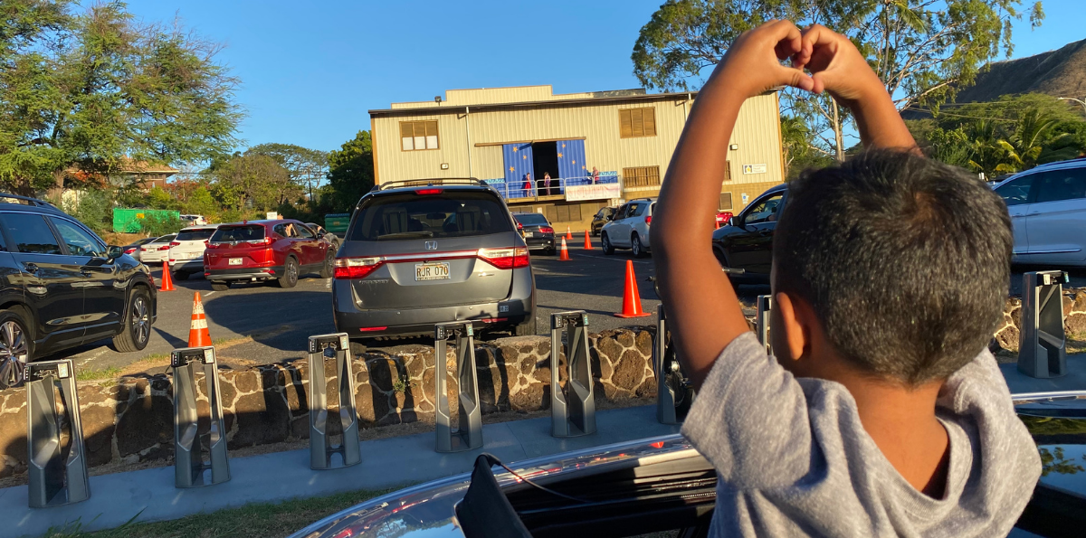 Boy holding up heart sign.